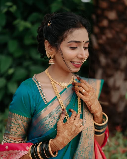 Bride in a teal and gold sari, looking down at her henna-decorated hands, from Pooja Salunkhe Makeover's portfolio