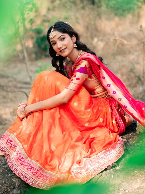 Seated outdoor portrait with an orange skirt, pink drape and softly styled hair, from Pooja Salunkhe Makeover's portfolio