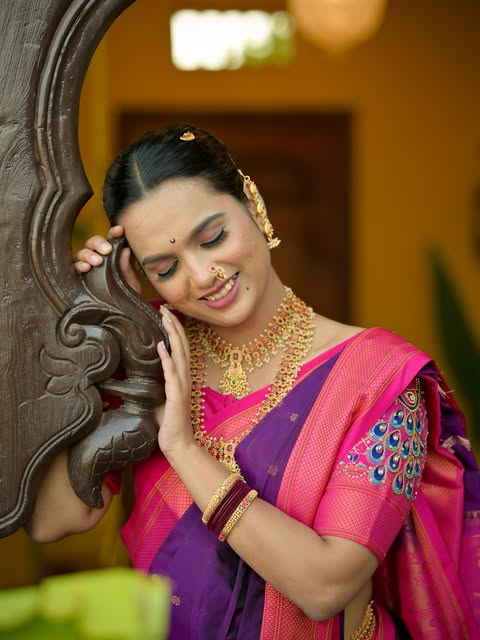 Makeup and softly styled hair with a purple and pink sari, photographed beside a carved doorway, from Pooja Salunkhe Makeover's portfolio